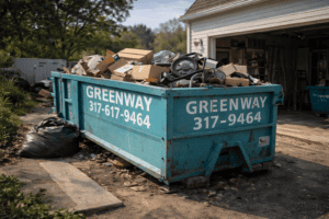 A blue roll-off dumpster at a residential job site surrounded by renovation debris and tools, ready for a home improvement project.